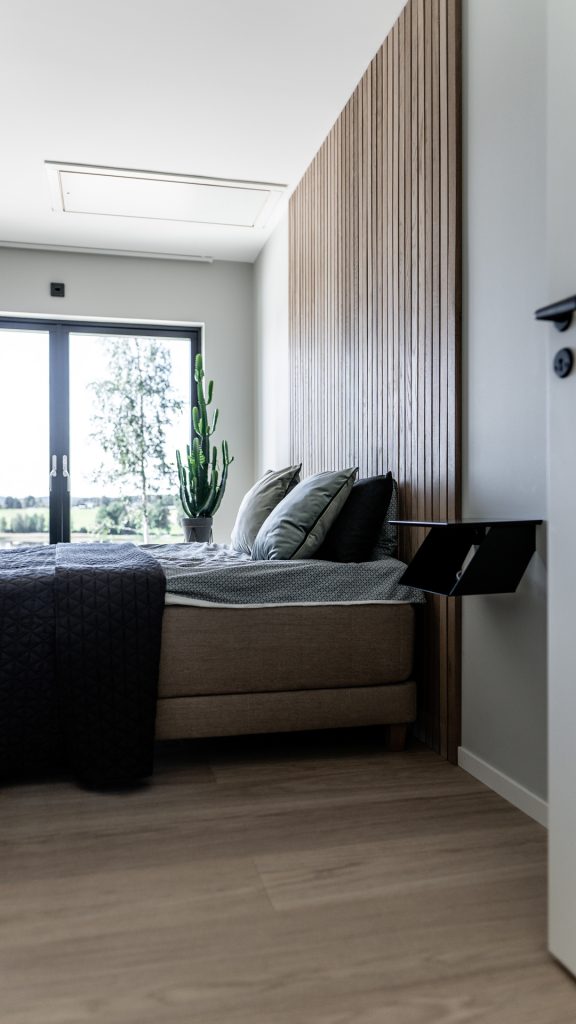 Sovrum i Villa Avaberg med träpanel bakom sängen och stort fönster