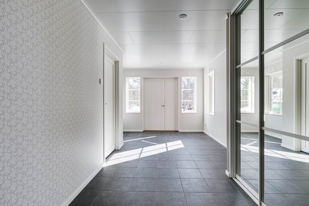 Hall i Villa Lögdeå med klinkergolv, garderobsdörrar och ljusa ytterdörrar