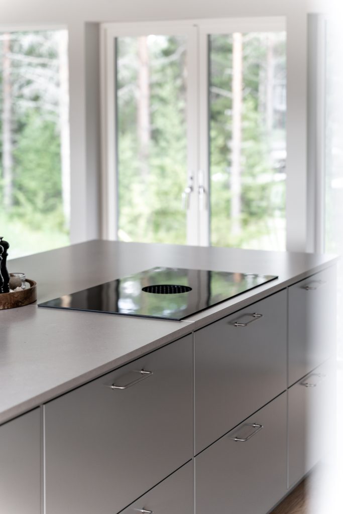 Kök i Villa Fällfors med grå luckor, induktionshäll och fönster mot skogen