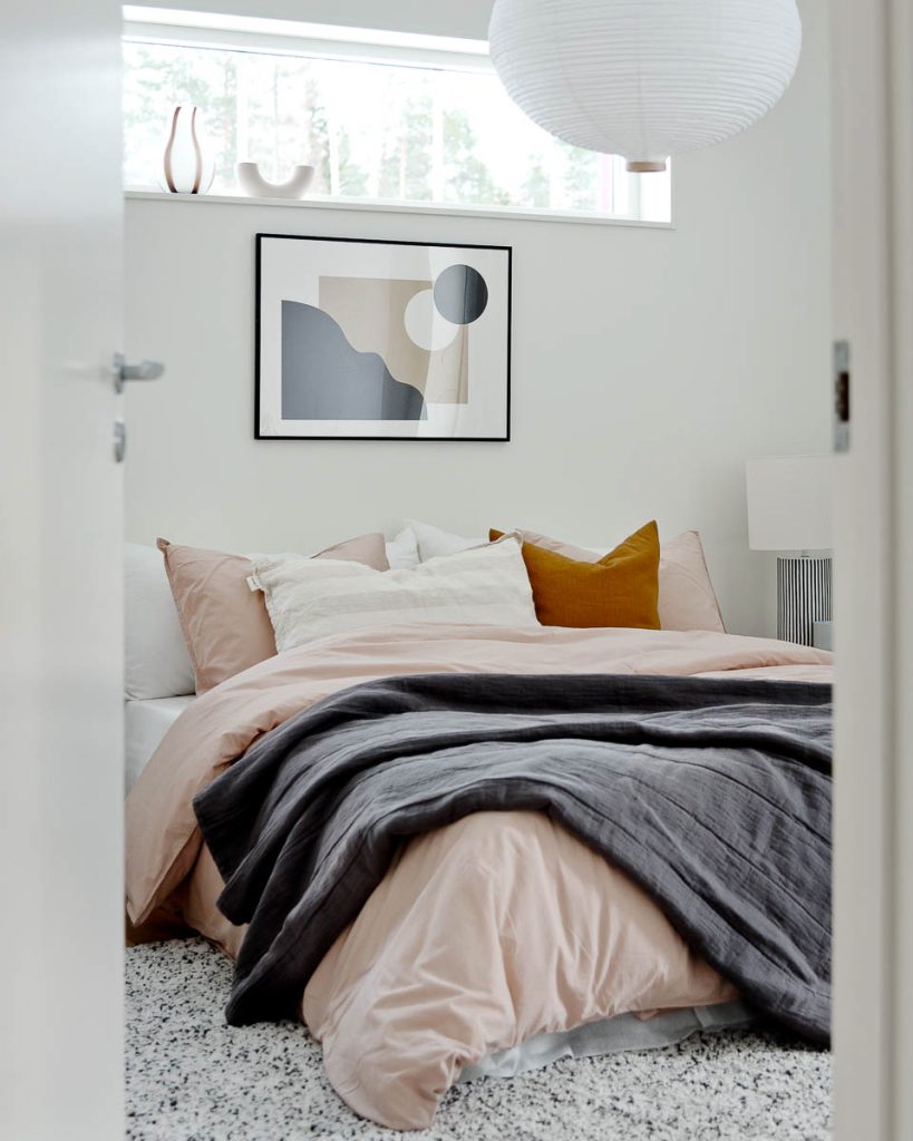 Sovrum i Villa Tallbacken med rosa sängkläder och grå pläd