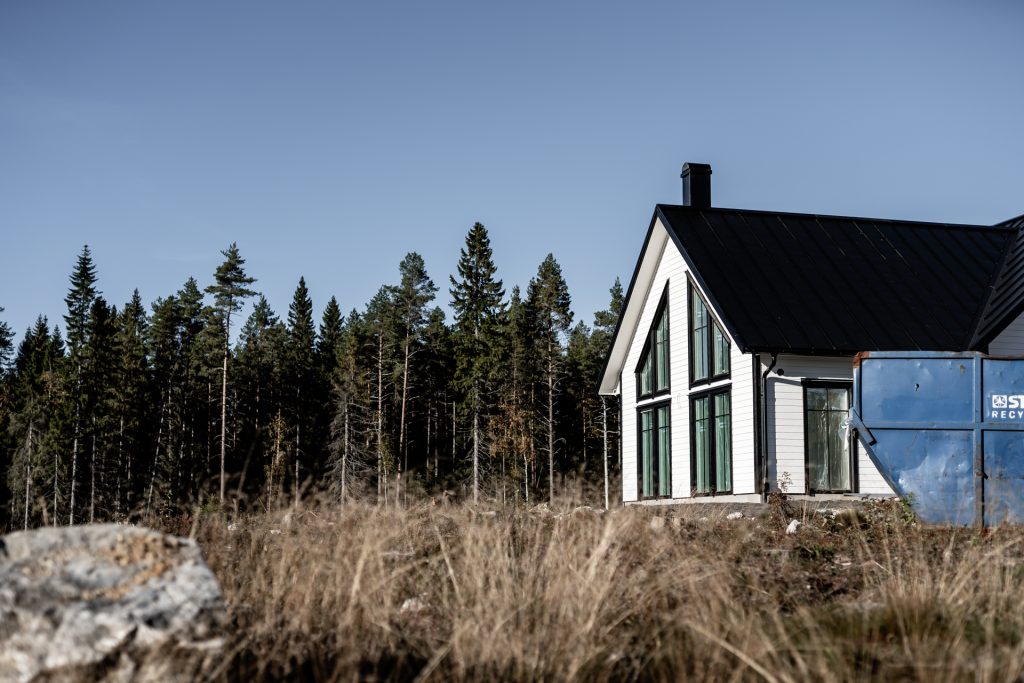 Villa Fällfors – vitt hus med svart tak och stora glaspartier vid skogen