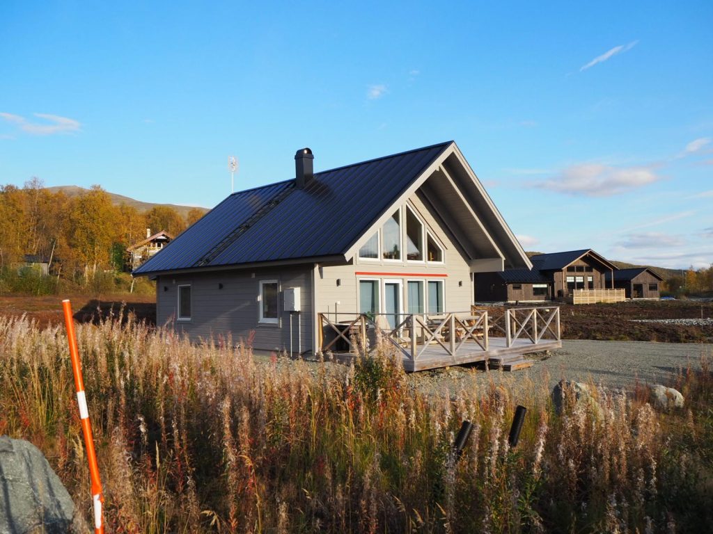 TH70L Pikebacken – fjällstuga med stora gavelfönster och altan i höstlandskap